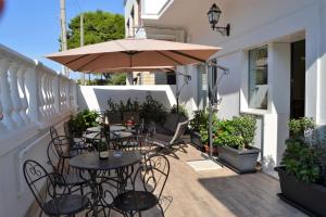 een patio met tafels en stoelen en een parasol bij Bed and Breakfast Sun Wine in Taranto