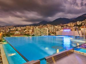a large swimming pool with a city in the background at Princessa Hotel in Jounieh