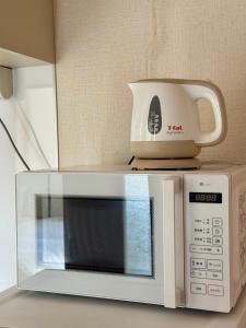 a white microwave with a coffee pot on top of it at KANAU in Tokyo