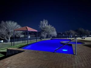 a blue swimming pool at night with a gazebo at Villa by The Vaal River in Vanderbijlpark