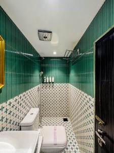 ein grün gefliestes Badezimmer mit Toilette und Waschbecken in der Unterkunft Palm Breeze Hotel - Colaba in Mumbai