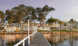 a dock in a marina with chairs and a building at The Beachcomber Hotel & Resort, an Ascend Collection Resort in Toukley