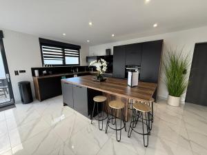 eine Küche mit einer Insel mit Hockern und einer Theke in der Unterkunft Villa Princesse neuve & grand standing ! in Valmont + 107 Fotos