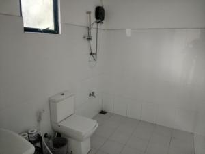 een witte badkamer met een toilet en een raam bij Goyambokka Beach front pool resort in Tangalle +14 foto's