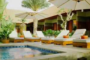 un complexe avec piscine, chaises longues et parasols dans l'établissement Kesumasari Living, à anur