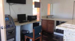 eine Küche mit einem Schreibtisch mit Stuhl und einer Maschine in der Unterkunft Coast Motel in Signal Hill