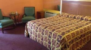 ein Hotelzimmer mit einem Bett und zwei Stühlen in der Unterkunft Coast Motel in Signal Hill