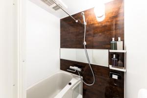 Das Bad ist mit einer Badewanne mit einem Duschkopf ausgestattet. in der Unterkunft AYA HOTELS 博多 1st in Fukuoka + 8 Fotos