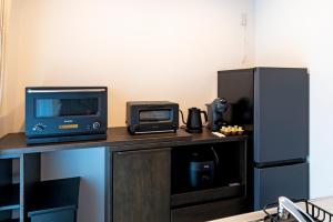 ein Computer und ein Monitor auf einem Schreibtisch mit einem Kühlschrank in der Unterkunft AYA HOTELS 博多 1st in Fukuoka