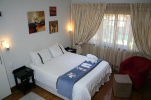 a bedroom with a white bed and a red chair at Thembelihle B&B in Pietermaritzburg