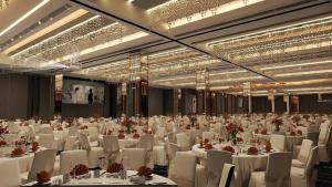 a banquet hall with white tables and chairs and chandeliers at The Everly Lhesson Kuching in Kuching +56 photos