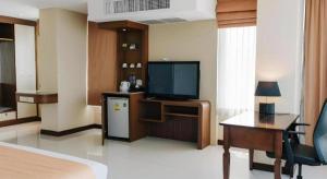 ein Hotelzimmer mit einem Bett, einem TV und einem Schreibtisch in der Unterkunft Aramis Hotel in Nakhon Sawan