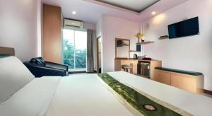 ein Hotelzimmer mit einem großen Bett und einem Fernseher in der Unterkunft The Loom Rangsit in Ban Lam Phak Kut