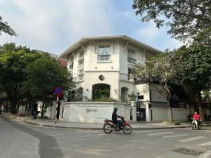 a person riding a bike in front of a white building at Phương Anh 303DM2 in Hanoi