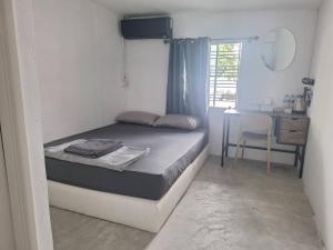 a small bedroom with a bed and a desk and a window at Phangan backpacker in Haad Rin