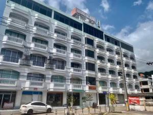 ein weißes Gebäude mit einem davor geparkten Auto in der Unterkunft Grand PL Hotel in Phatthalung