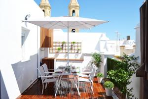 un pequeño balcón con mesa, sillas y sombrilla en Ático Fenicia, en Cádiz