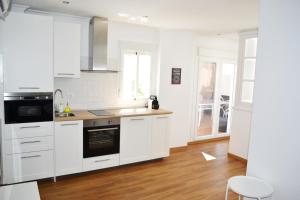 cocina con armarios blancos y suelo de madera en Ático Fenicia, en Cádiz