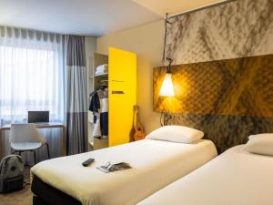 ein Hotelzimmer mit zwei Betten und einer Gitarre in der Unterkunft ibis Gent Centrum Opera in Gent