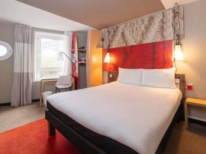 Habitación de hotel con cama grande y cabecero rojo en ibis Portsmouth, en Portsmouth 136 fotos más
