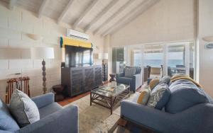 a living room with blue couches and a television at Maltese Falcon - by ZenBreak in Saint Philip