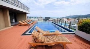 a balcony with chairs and a swimming pool on a building at Elegancy Sansabai Hotel in Patong Beach