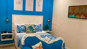a bedroom with a bed with a blue wall at Villa De Lasannta - by ZenBreak in Christ Church