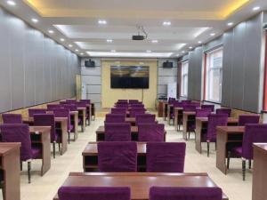 Una sala de conferencias con sillas moradas y una pantalla. en GreenTree Inn Langfang GuAn County Xinyuan Street Express Hotel, en Gu'an