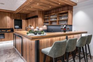 a kitchen with a bar with chairs and wine glasses at Hotel Antony in Ischgl