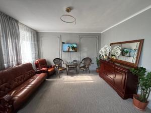 a living room with a leather couch and a table at BT City Hotel in Gornyy Gigant