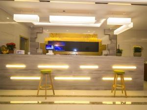 a lobby with a bar with two yellow stools at GreenTree Inn Weifang Kuiwen District Beiwang Jiale in Weifang