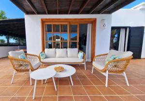a patio with a couch and two chairs and a table at Costa Christina con piscina climatiza in Yaiza