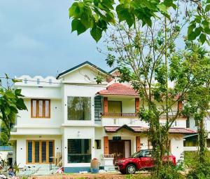 a house with a red car parked in front of it at Zonooro Homestay Vythiri in Vythiri