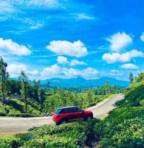 a red car is driving down a road at Zonooro Homestay Vythiri in Vythiri