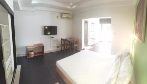 a white bedroom with a bed and a table at "FLORIDA" - Guest-house Tamatave in Toamasina