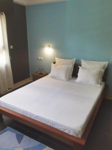een groot bed met witte lakens en kussens bij FLORIDA Guest-house in Toamasina +25 foto's