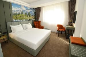 a bedroom with a large white bed and a desk at Hotel Aleksandar Conference & Spa in Žabljak