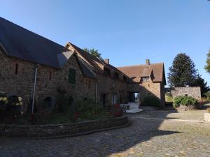 ein altes Steingebäude mit einer Einfahrt davor in der Unterkunft Maisonnette meublée à la campagne in Ernée