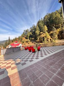 a group of red chairs sitting on a tiled patio at Raj Hotel and Restaurant in Bhadarwāh