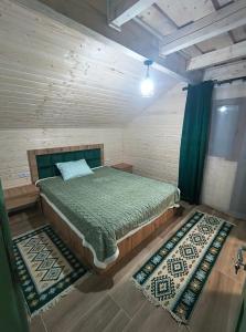 een slaapkamer met een bed en twee tapijten bij Casa din fagi in Munună