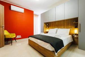 a bedroom with a large bed with an orange wall at Stylish 2BR Retreat, Central Location, Few Steps from the Sea by QuickTrips in Marsaskala