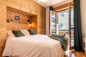 een slaapkamer met een groot wit bed in een kamer met houten wanden bij HelloCHALET TrackSide House - Ski-In Ski-Out Apartment on the Cretaz Slopes in Breuil-Cervinia