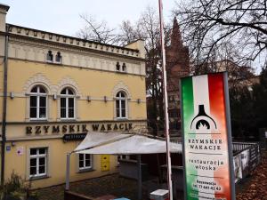 Ein Schild vor einem Gebäude mit einer Flasche Wein in der Unterkunft Rzymskie wakacje in Oppeln