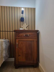 Neben einem Bett steht ein Holzschrank mit einem Seestern darauf. in der Unterkunft M&M apartments in Monclassico