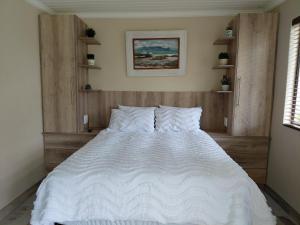 ein Schlafzimmer mit einem Bett mit weißen Laken und Kissen in der Unterkunft Place of Old D in Eersterivier