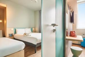 a hotel room with a bed and a bed and a room at ibis budget Valence Nord Plateau des Couleures in Saint-Marcel-lès-Valence