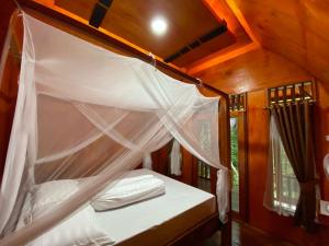 a bedroom with a canopy bed in a tiny house at Batu Katak Jungle River & Trekking in Bukit Lawang +285 photos