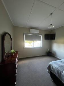 a bedroom with a bed and a dresser and a mirror at Spring Valley Cottage in Parkes