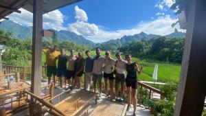 a group of people standing on a deck with mountains in the background at Meadow Mai Chau Homestay in Mai Chau
