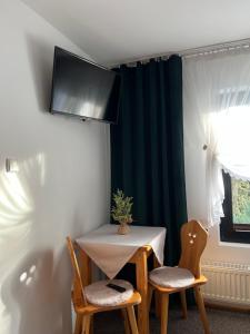 a table with two chairs and a tv on a wall at AgroDomek Rzepiska in Rzepiska